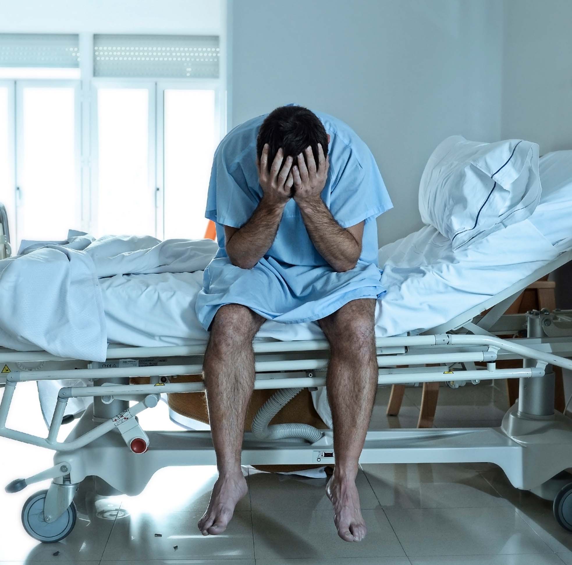 Man distressed sitting on a hospital bed