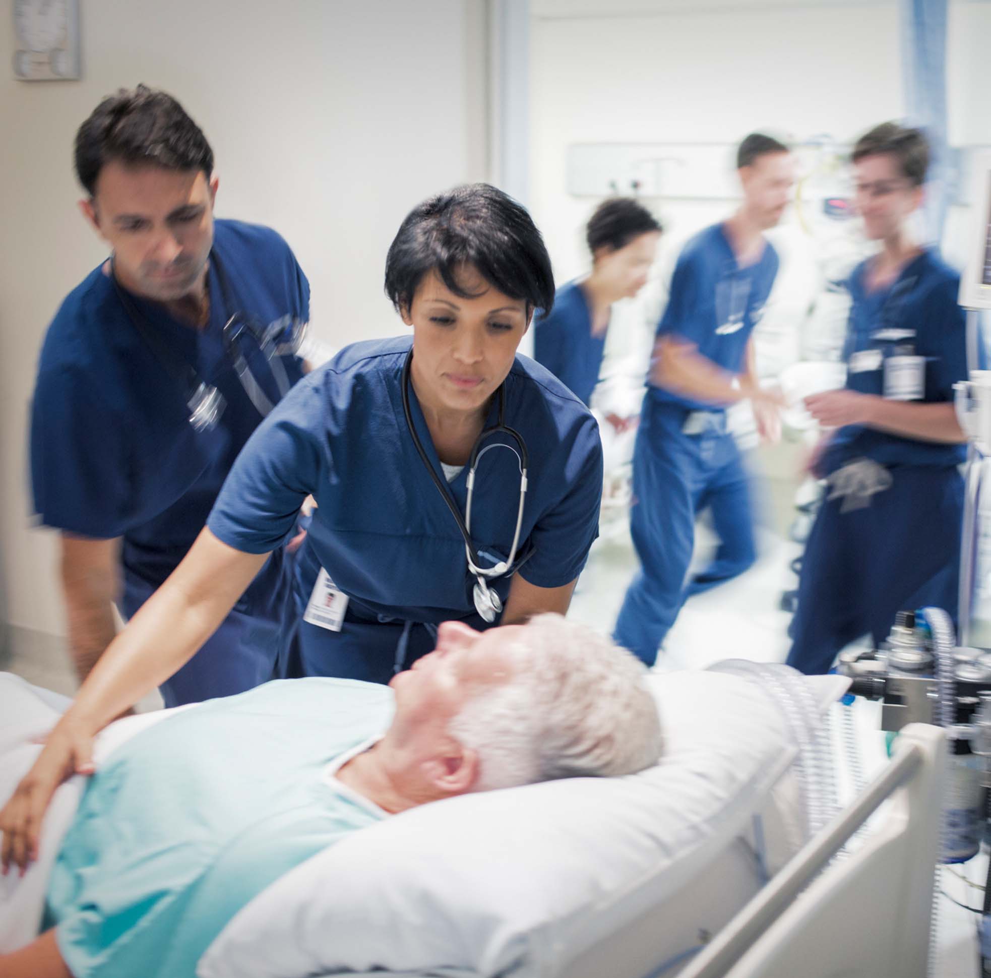 Woman wheeling a patient on a hospital bed.